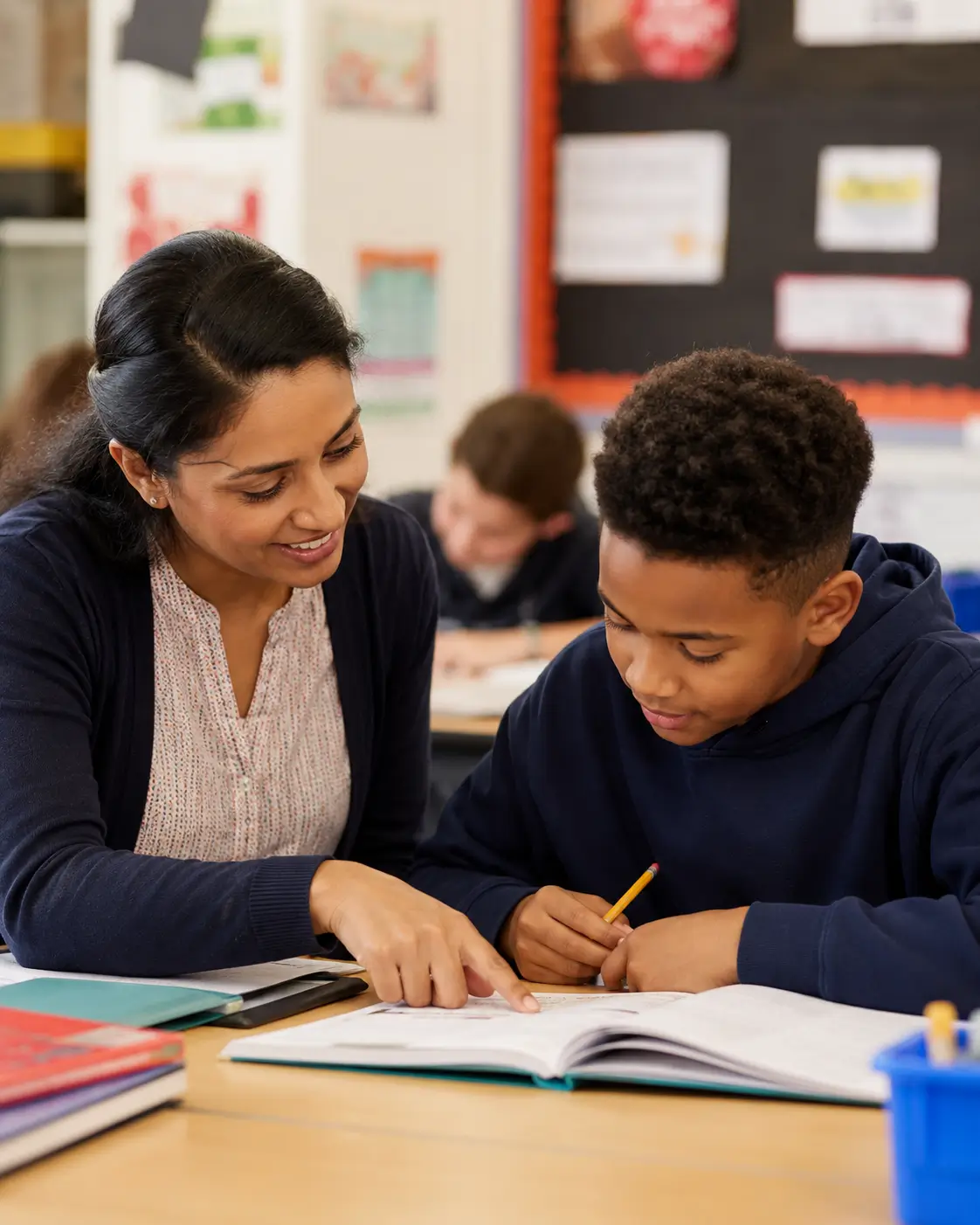 A UK primary school classroom with a teacher helping a student at a desk